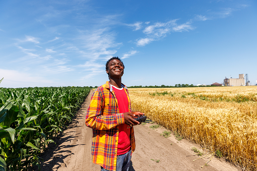Pascal Izere, masters student in BSE, launches an autonomous drone photographing a field of triticale at the research fields at 84th and Havelock. Biological Systems Engineering fieldwork with drones for phentotyping fields. June 27, 2022.  Photo by Craig Chandler / University Communication