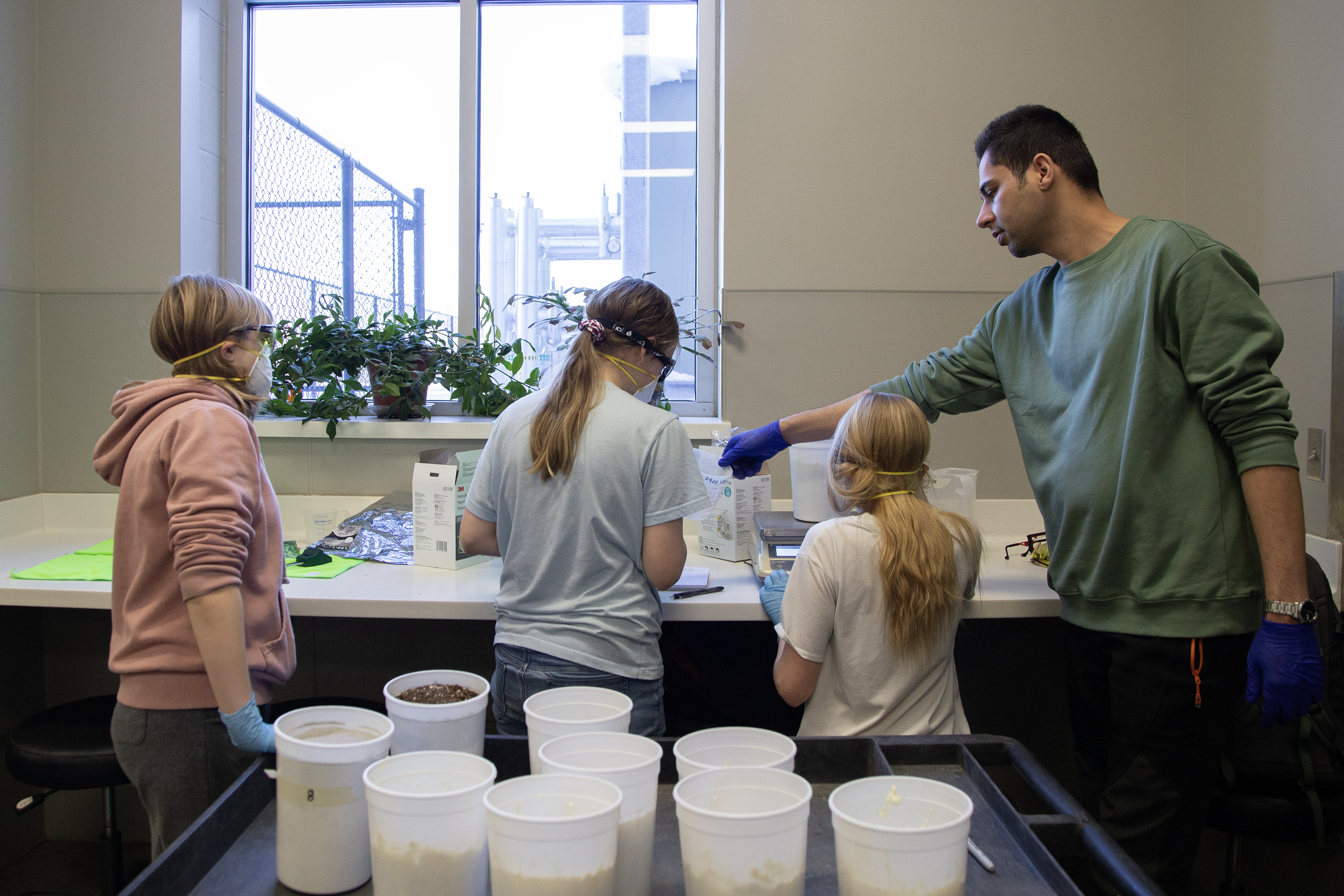 Ehsan Fazayeli, Biological Systems Engineering graduate student, helps Dawes Middle School students measure lunar soil simulant mixes. 