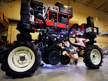 two people working on robotic tractor