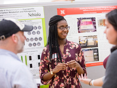 students talking in front of presentation poster